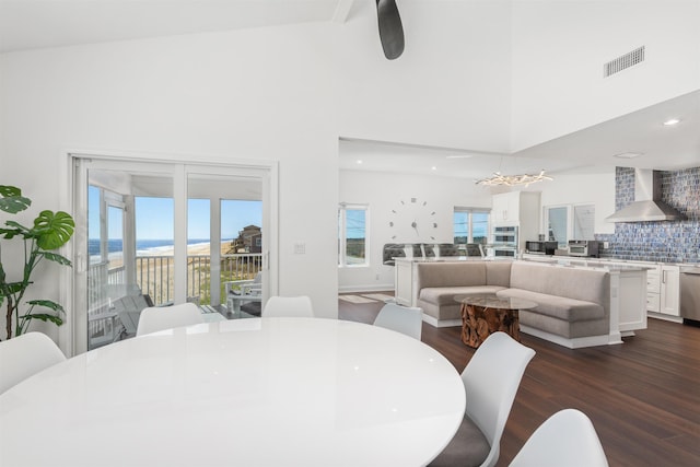 dining area featuring a wealth of natural light, a chandelier, a towering ceiling, and dark wood-style flooring