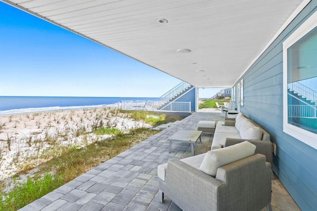 view of patio / terrace with a view of the beach, stairway, and a water view