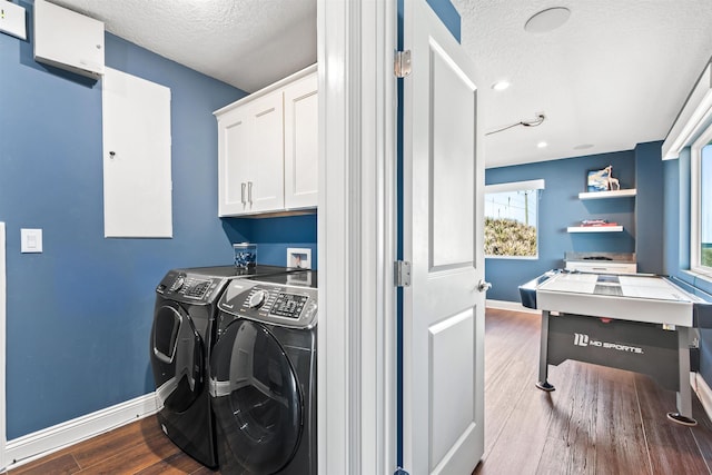 laundry room with washing machine and clothes dryer, cabinet space, a textured ceiling, and wood finished floors