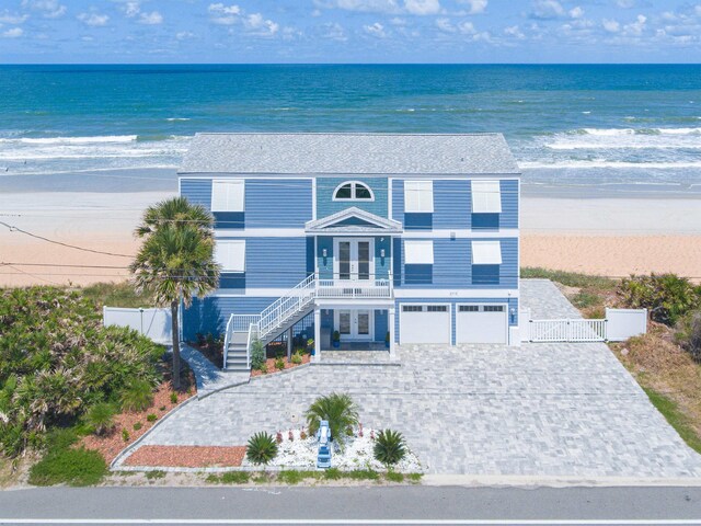beach home with stairs, french doors, decorative driveway, a garage, and a gate