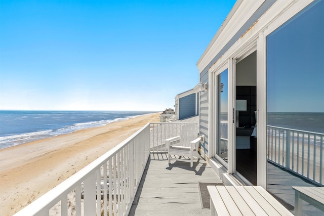 balcony featuring a view of the beach and a water view