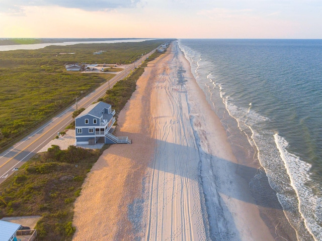 aerial view at dusk with a view of the beach and a water view