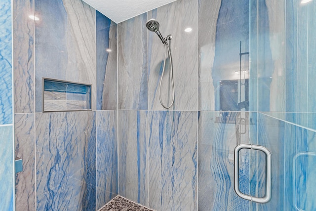 full bathroom with a marble finish shower and a textured ceiling