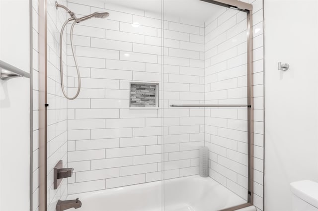 bathroom with enclosed tub / shower combo and toilet