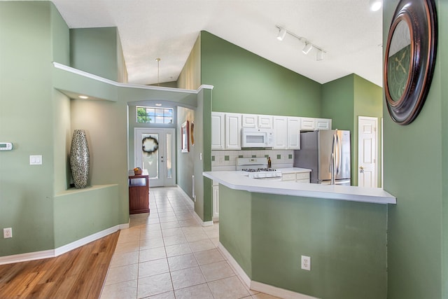 1505 Sundown Ln, Clermont, FL 34711 - kitchen with white appliances, white cabinetry, baseboards, high vaulted ceiling, and light countertops