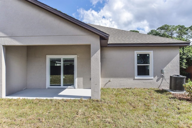 rear view of property featuring a patio area, a yard, and central AC