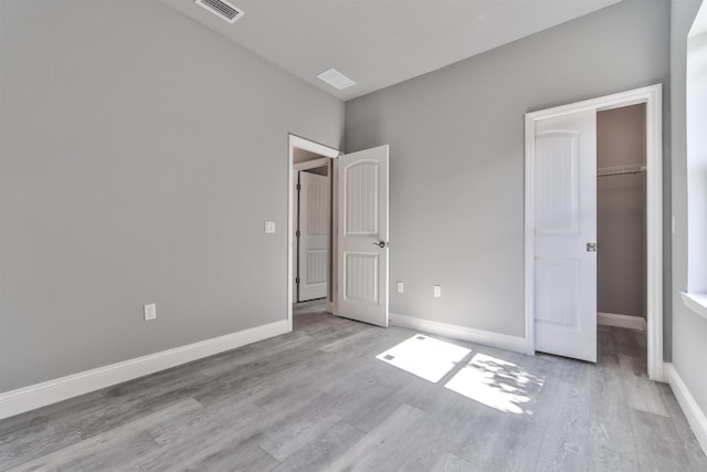 unfurnished bedroom with a walk in closet, light wood-type flooring, and a closet