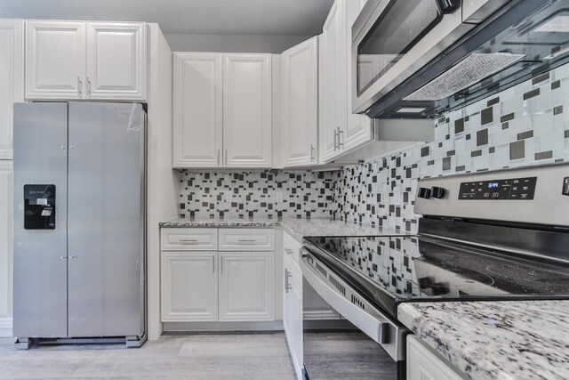 kitchen with backsplash, white cabinets, light wood-type flooring, and appliances with stainless steel finishes