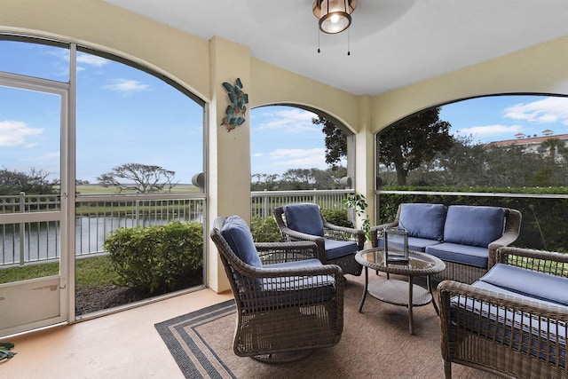 sunroom / solarium with a water view and ceiling fan