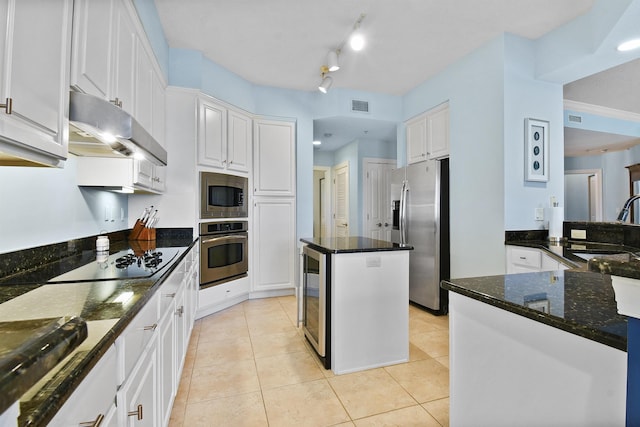 kitchen featuring white cabinets, a kitchen island, stainless steel appliances, and dark stone counters