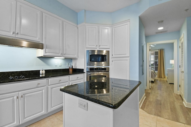 kitchen with white cabinets, stainless steel appliances, and dark stone counters