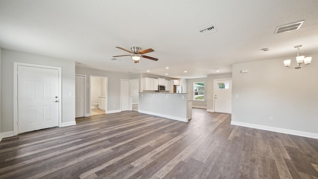 unfurnished living room with ceiling fan with notable chandelier and dark hardwood / wood-style flooring