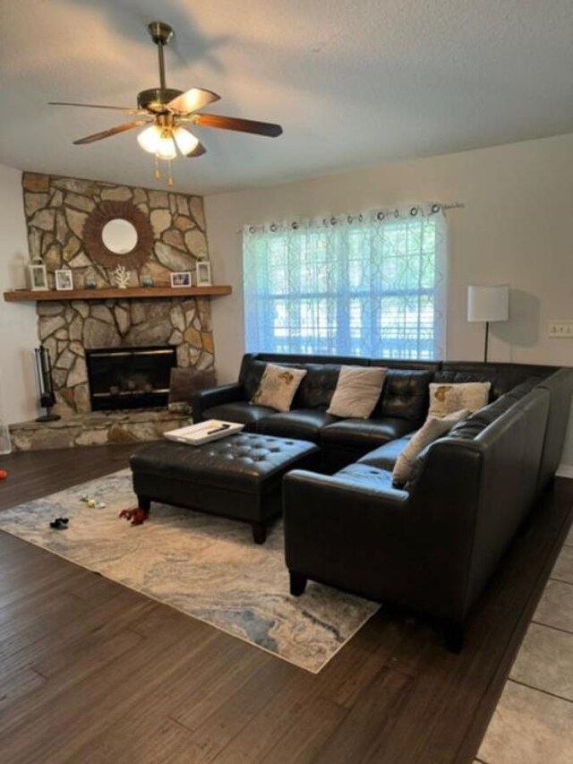 living room with ceiling fan, a fireplace, light hardwood / wood-style floors, and a textured ceiling