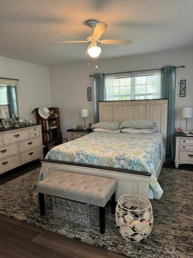 bedroom with ceiling fan, dark hardwood / wood-style flooring, and a textured ceiling