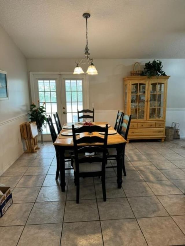 dining room with tile patterned flooring, lofted ceiling, french doors, and an inviting chandelier