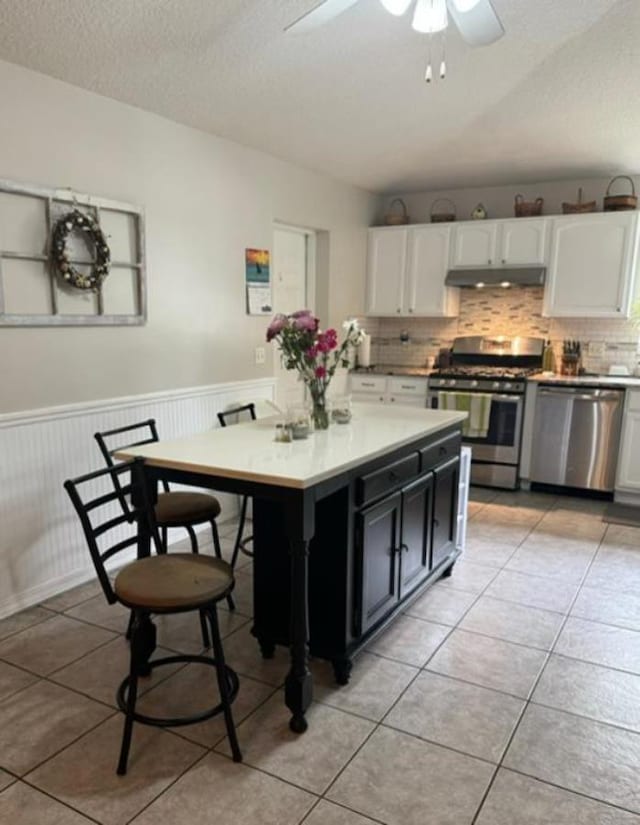 kitchen featuring appliances with stainless steel finishes, backsplash, ceiling fan, light tile patterned floors, and white cabinetry