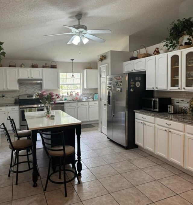 kitchen with light tile patterned flooring, white cabinetry, appliances with stainless steel finishes, and tasteful backsplash