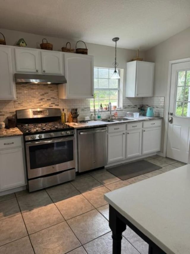 kitchen with a wealth of natural light, white cabinetry, stainless steel appliances, and decorative light fixtures