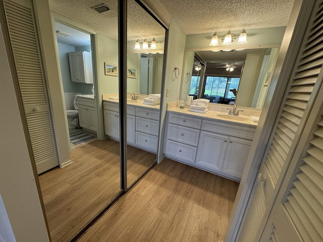 bathroom with vanity, toilet, hardwood / wood-style floors, and a textured ceiling