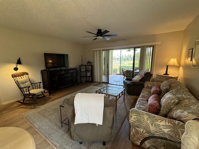 living room with ceiling fan, a textured ceiling, and wood-type flooring