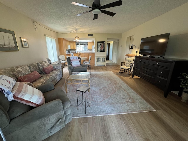 living room with wood-type flooring, a textured ceiling, and ceiling fan