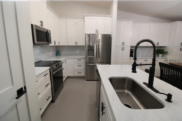 24 Aledo Ct, Saint Augustine, FL 32086 - kitchen with tasteful backsplash, appliances with stainless steel finishes, white cabinets, vaulted ceiling, and a sink