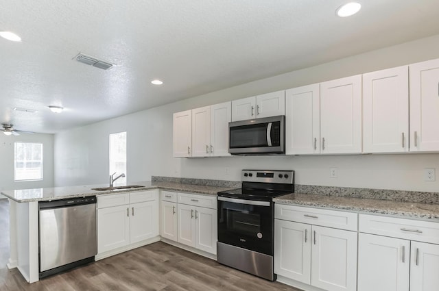 kitchen with white cabinets, stainless steel appliances, kitchen peninsula, and sink