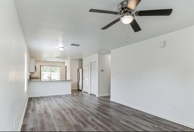 unfurnished living room featuring hardwood / wood-style flooring, ceiling fan, sink, and a textured ceiling