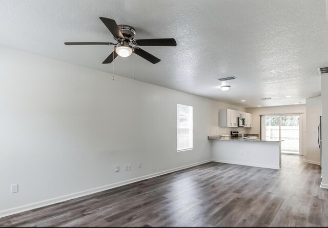 unfurnished living room with sink, ceiling fan, dark hardwood / wood-style flooring, and a textured ceiling