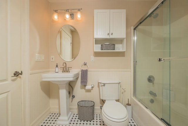 bathroom featuring combined bath / shower with glass door and toilet