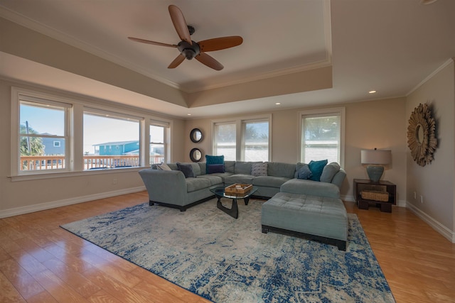 living room with crown molding, ceiling fan, a tray ceiling, and light hardwood / wood-style floors