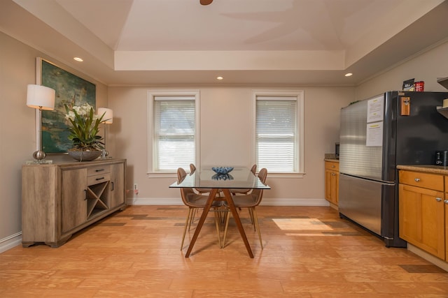 dining area featuring a raised ceiling and light wood-type flooring