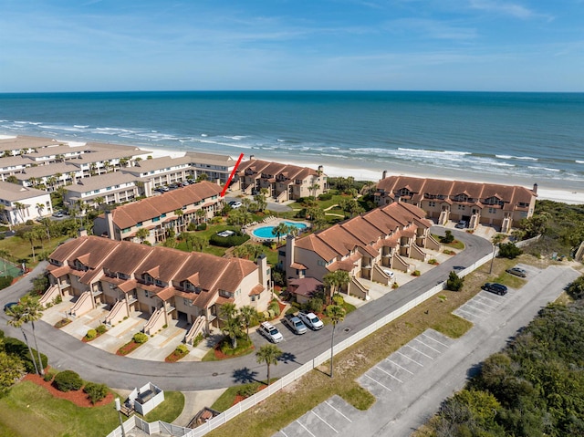 drone / aerial view featuring a water view, a residential view, and a beach view