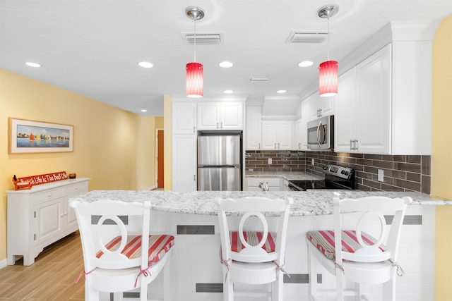 kitchen featuring a peninsula, appliances with stainless steel finishes, light stone counters, and tasteful backsplash