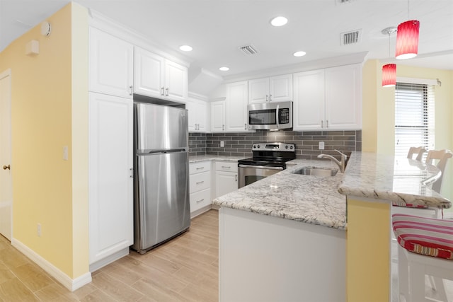 kitchen with appliances with stainless steel finishes, visible vents, a sink, and a peninsula