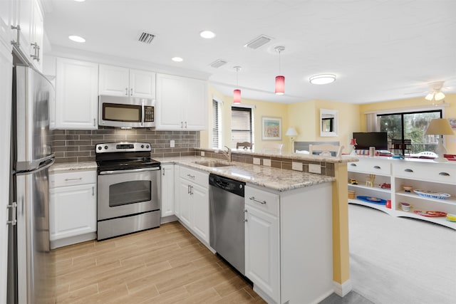 kitchen with stainless steel appliances, visible vents, backsplash, a sink, and a peninsula