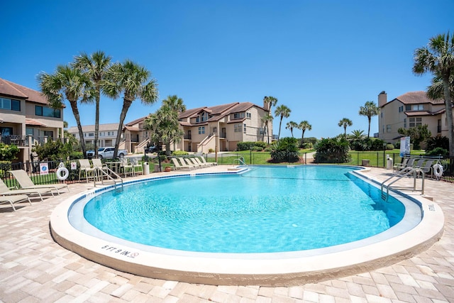 pool featuring a patio area, fence, and a residential view