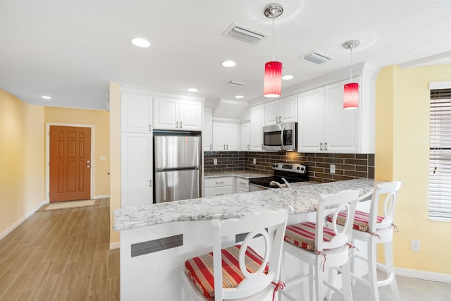 kitchen featuring a peninsula, visible vents, stainless steel appliances, and backsplash