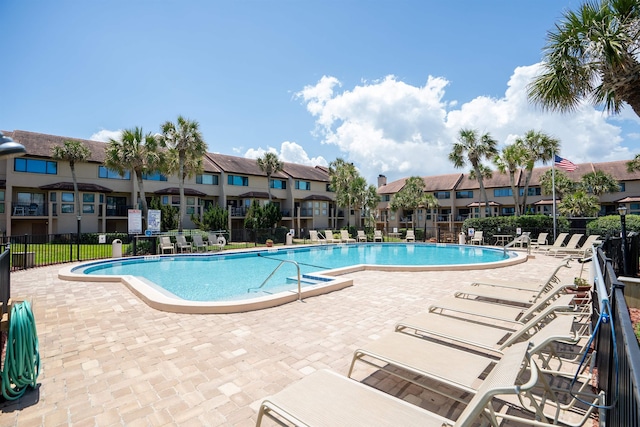 community pool with a residential view, a patio area, and fence