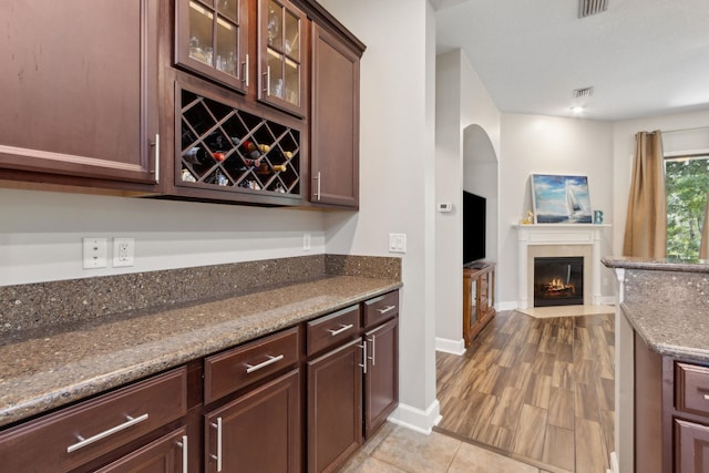 153 Savanna Preserve Ct, Saint Augustine, FL 32095 - kitchen featuring arched walkways, open floor plan, glass insert cabinets, dark stone countertops, and baseboards