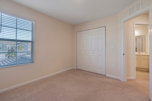 unfurnished bedroom featuring light colored carpet and a closet