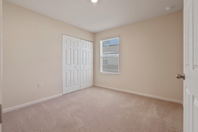 unfurnished bedroom with a closet and light carpet