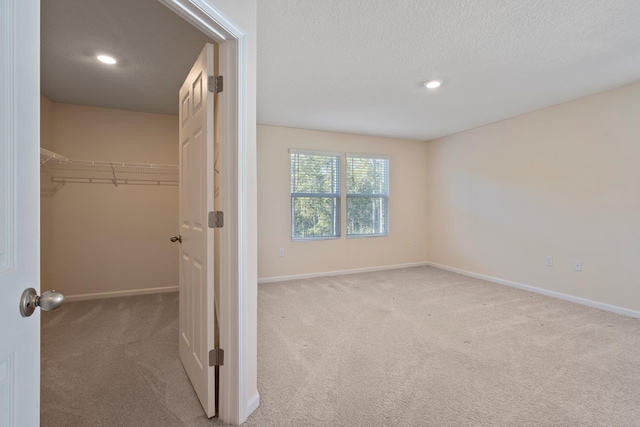 interior space with a textured ceiling, a closet, and light carpet