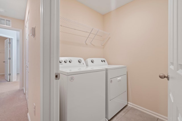 laundry area with light tile patterned floors and washing machine and clothes dryer