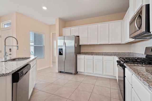 kitchen with light stone countertops, sink, white cabinets, and stainless steel appliances