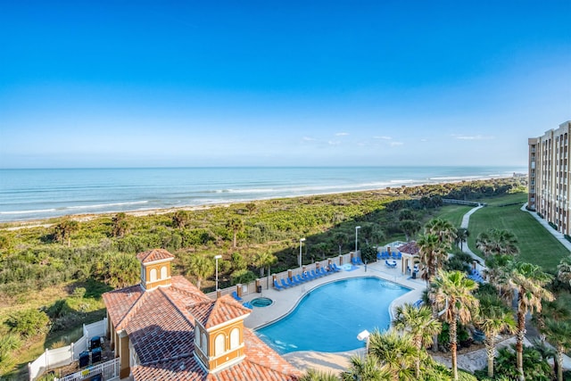 view of swimming pool featuring a water view, a patio, and a beach view