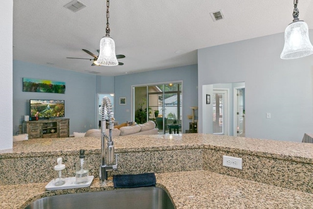 132 Fallen Timber Way, Saint Augustine, FL 32084 - kitchen with open floor plan, hanging light fixtures, a ceiling fan, light stone counters, and a textured ceiling