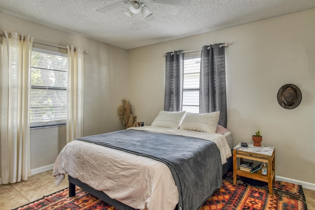 bedroom featuring ceiling fan, tile patterned flooring, and a textured ceiling