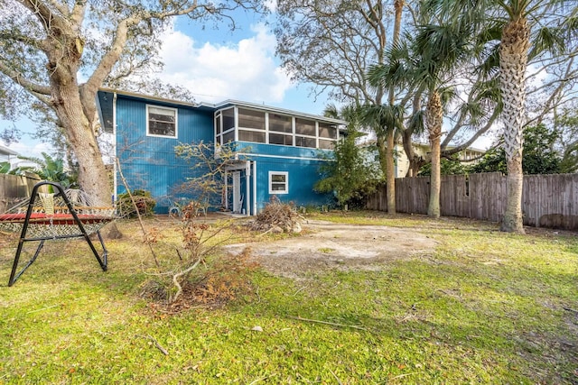 rear view of house featuring a sunroom and a yard