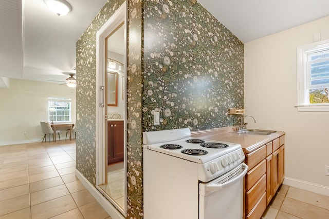 kitchen featuring a healthy amount of sunlight, light tile patterned flooring, electric stove, and sink